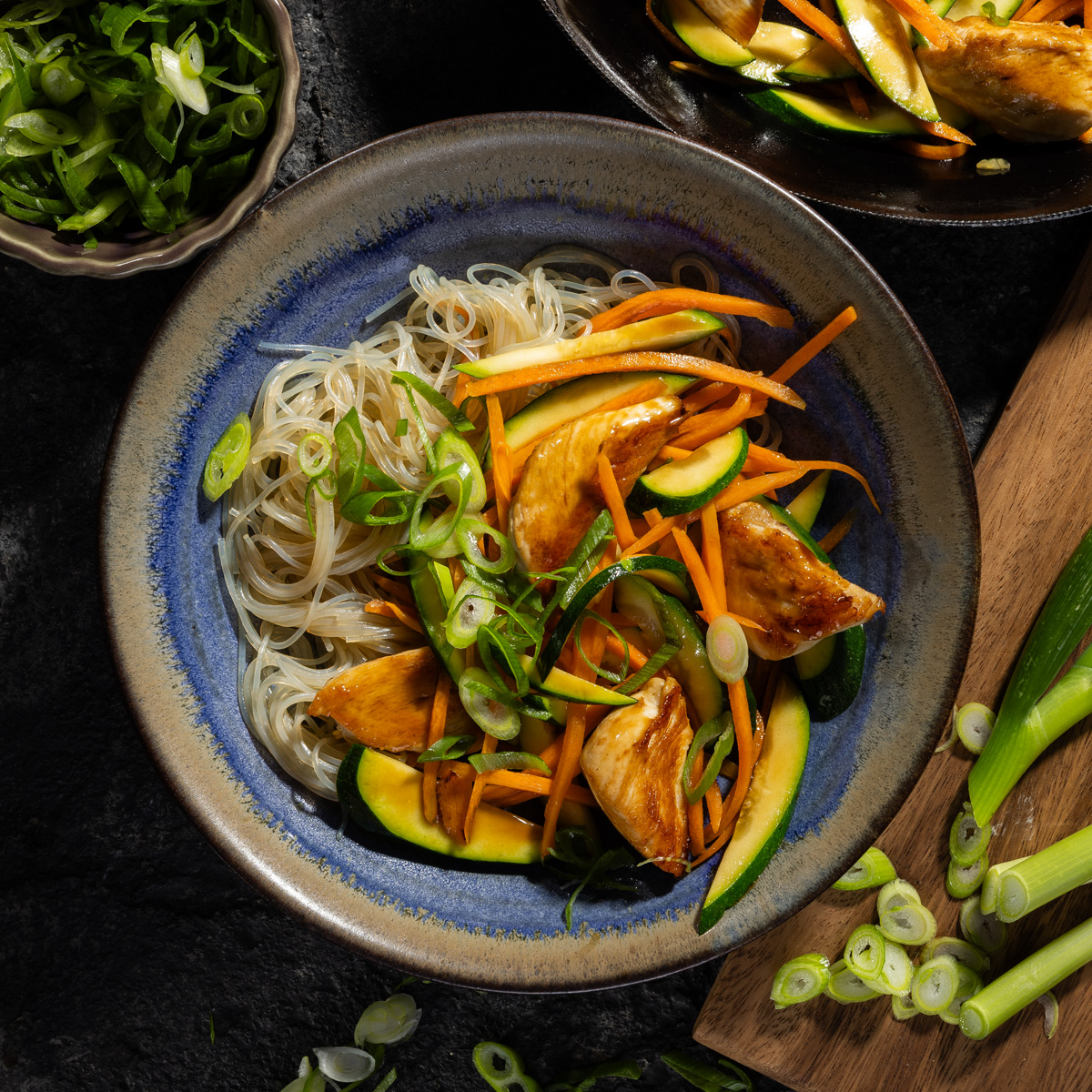 Eine schüssel mit Nudeln und Gemüse. Daneben Gemüse