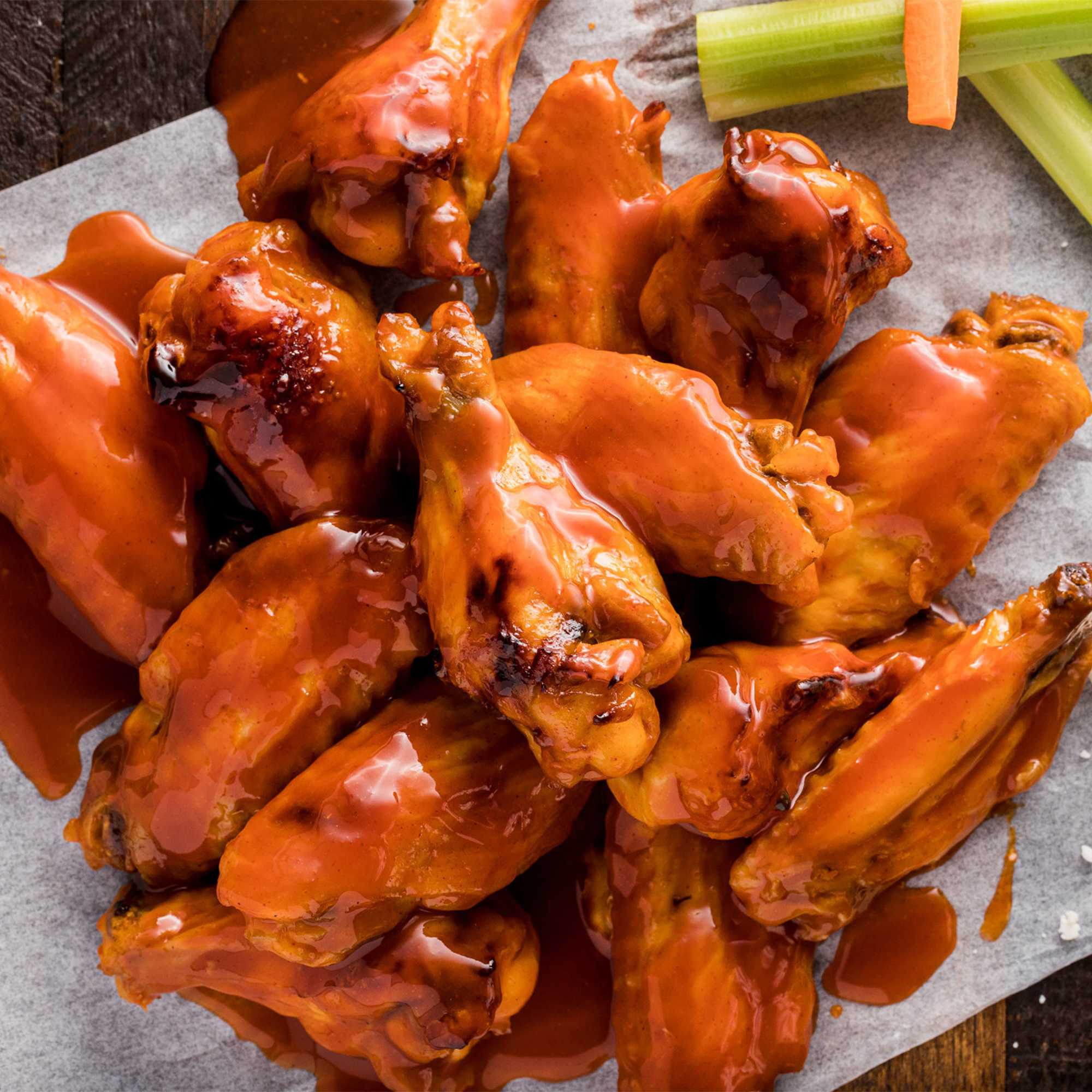 In der Mitte des Bildes sind mehrere Kentucky Style glazed Chicken Wings auf Backpapier zu sehen..