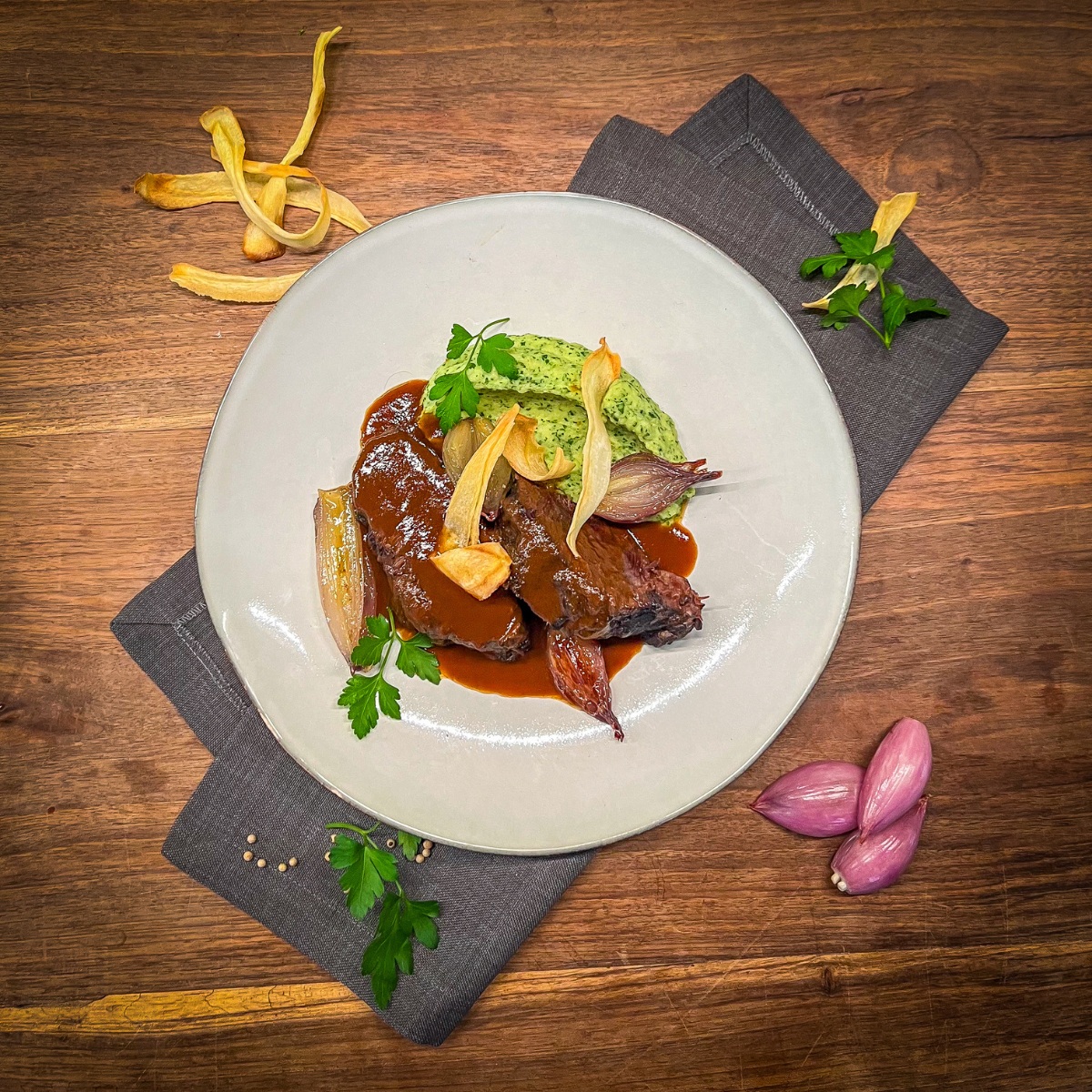 Rinderbäckchen auf einem Teller, verziert mit einzelnen Zutaten