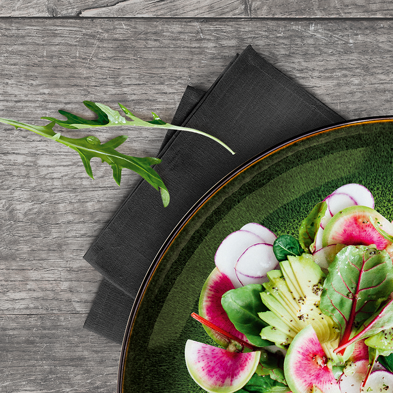 Ein Gericht symbolisch für die Bio-Küche, der eine Vielzahl von rohen Gemüsesorten auf einem grünen Teller zeigt.