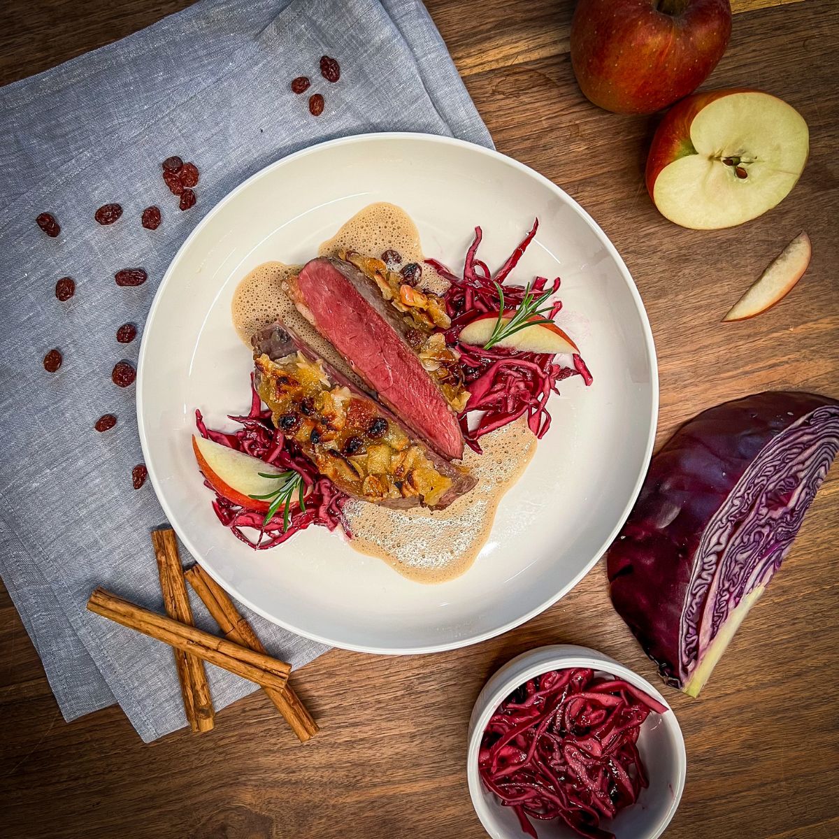 Entenbrust auf einem Teller mit Rotkohl, Äpfeln und Sauce