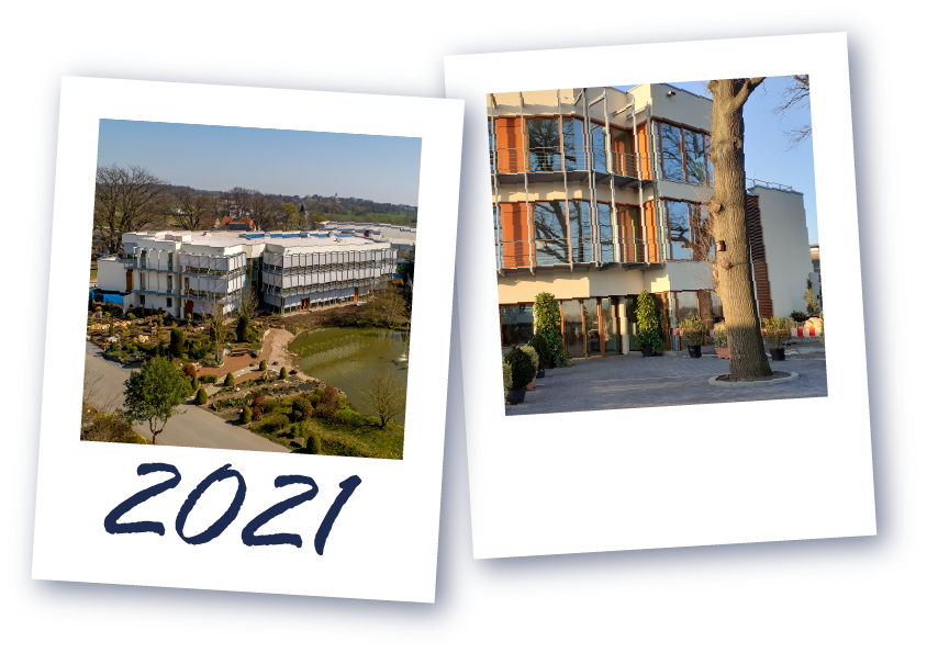 Ein modernes Gebäude mit Glasfassade & ein Baum vor einem mehrstöckigen Gebäude mit orangen Fensterläden, darunter die Jahreszahl '2021'.