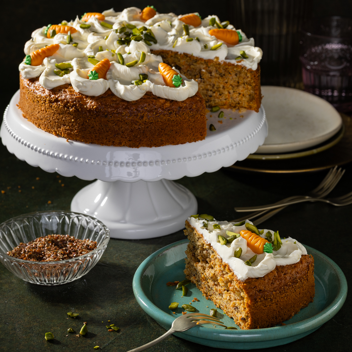 Ein veganer Karottenkuchen auf einem Kuchen Tablett, daneben ein einzelnes Stück des Kuchens auf einem Teller
