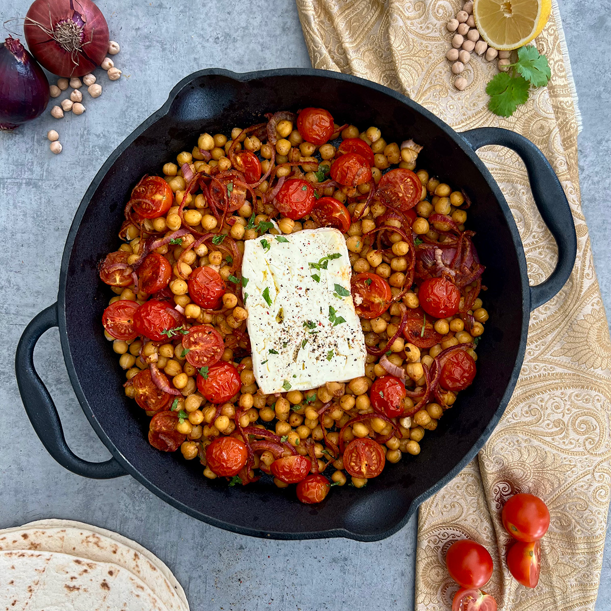gebackenerfetamitkicherebsen in einer Pfanne daneben zwiebeln,Zitrone, Tomate