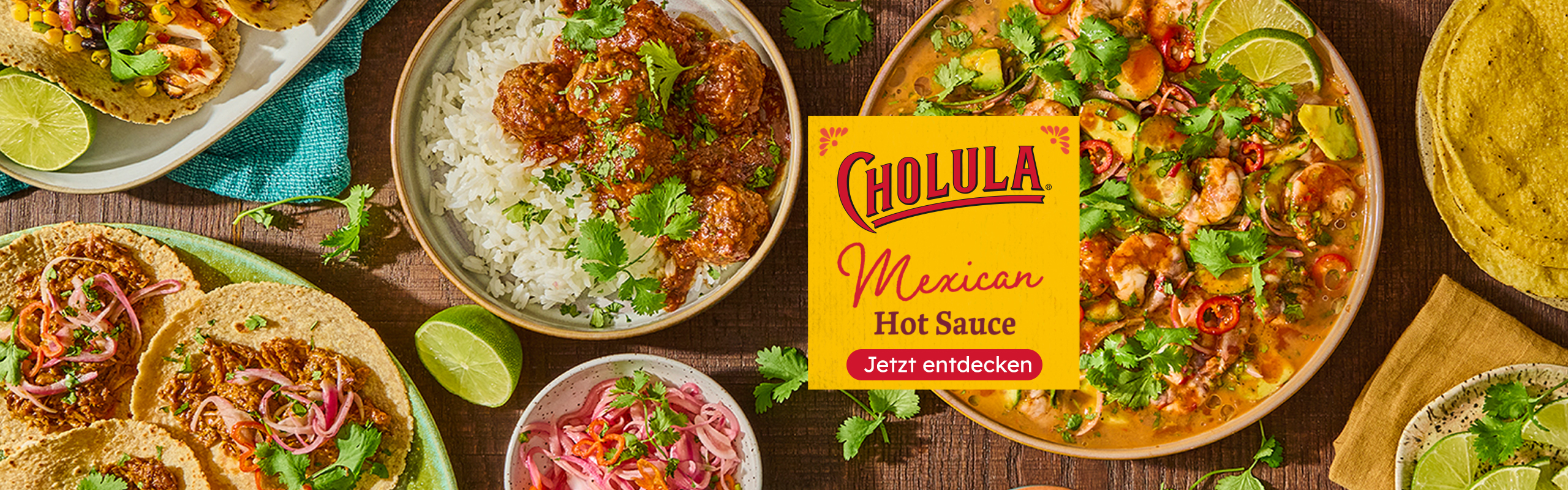 Gedeckter Tisch mit mexikanischen Gerichten hinter dem Logo Cholula.