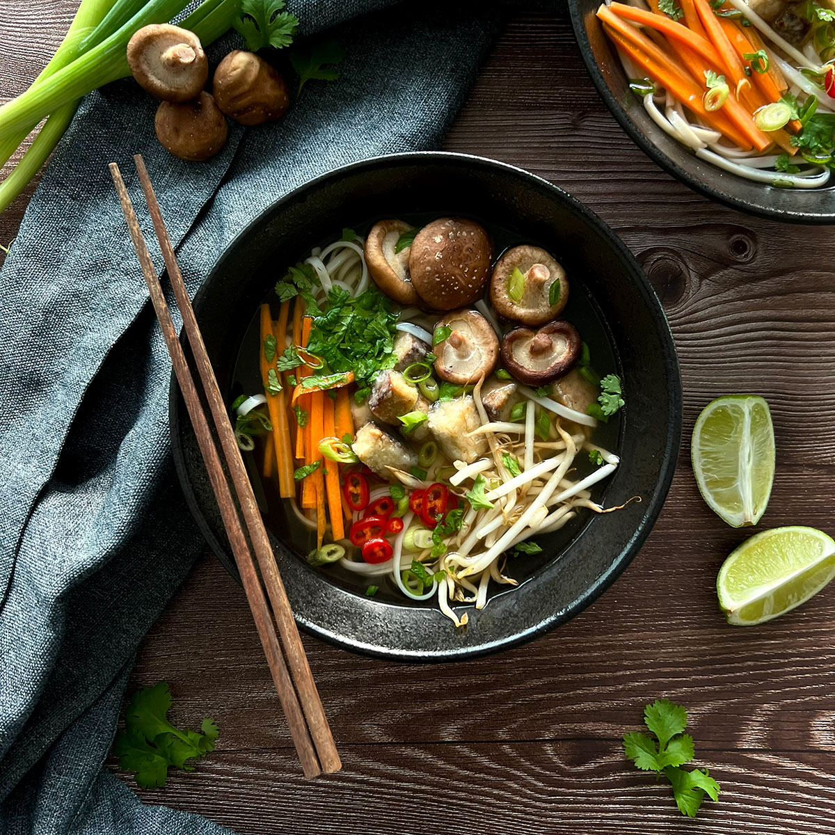 Pho Suppe in einer Schüssel an den seiten frisches Gemüse