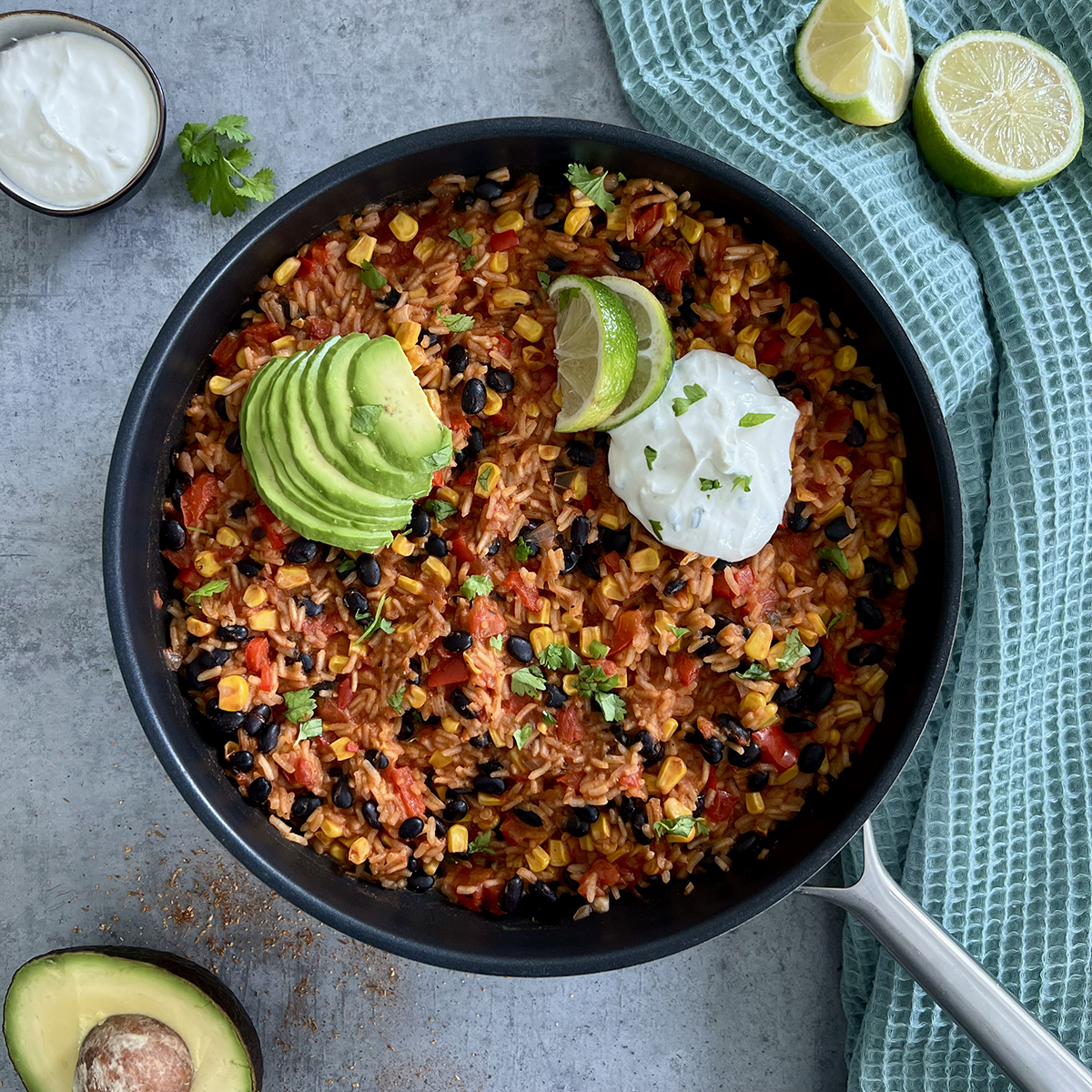 Das Bild zeigt eine Pfanne mit dem Gericht das getoppt ist mit Avocado und einem Dip. Beides steht auch daneben.