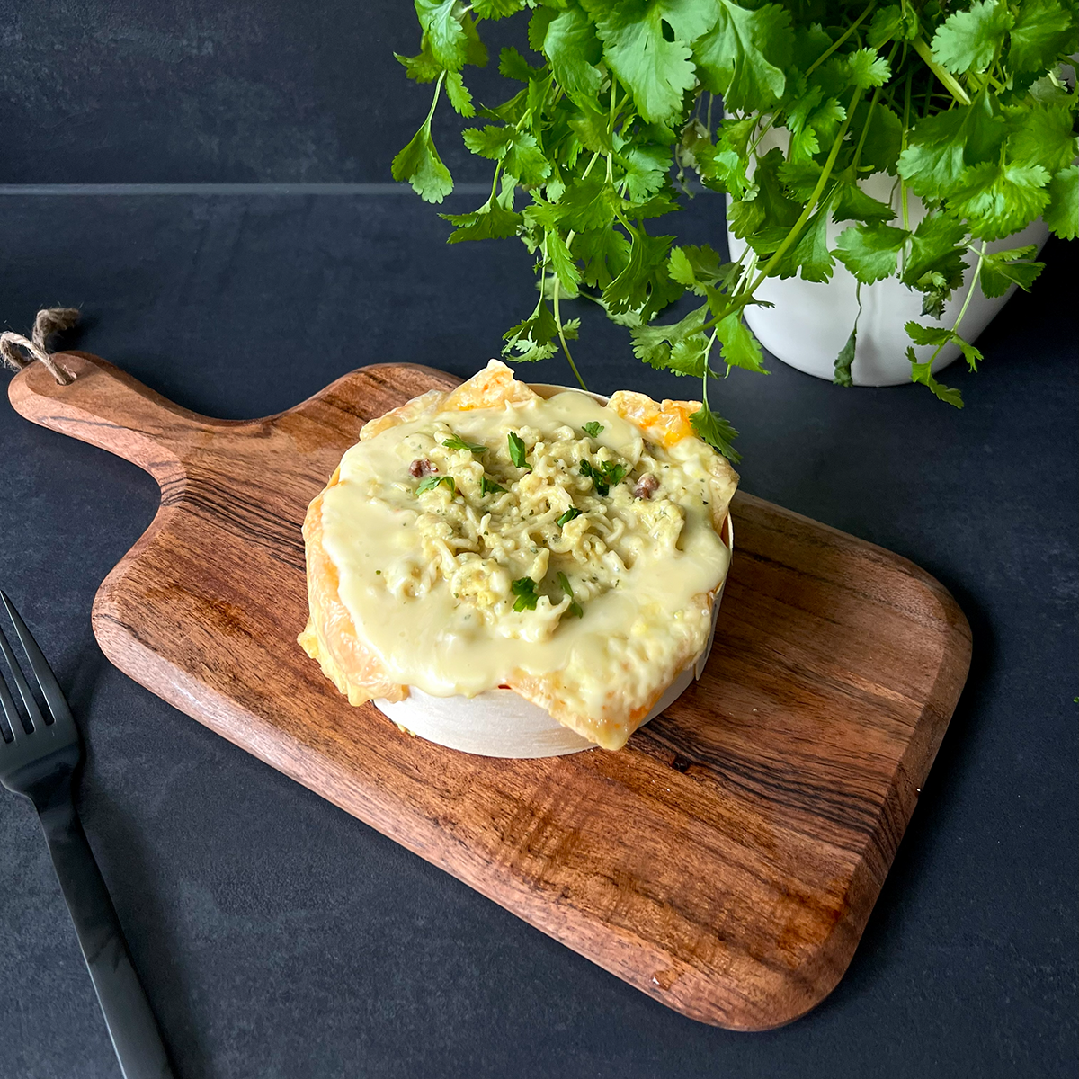 ofenkäse getoppt mit carbonara Nueln auf einem Holzbrett