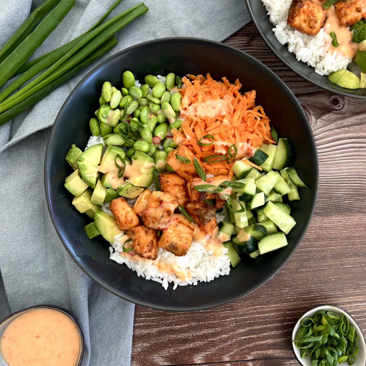 Das Bild zeigt eine Bowl, die Hauptkomponente ist Reis darüber liegt Hänchen, Avocado, Gurke, Möhren und Edamame.