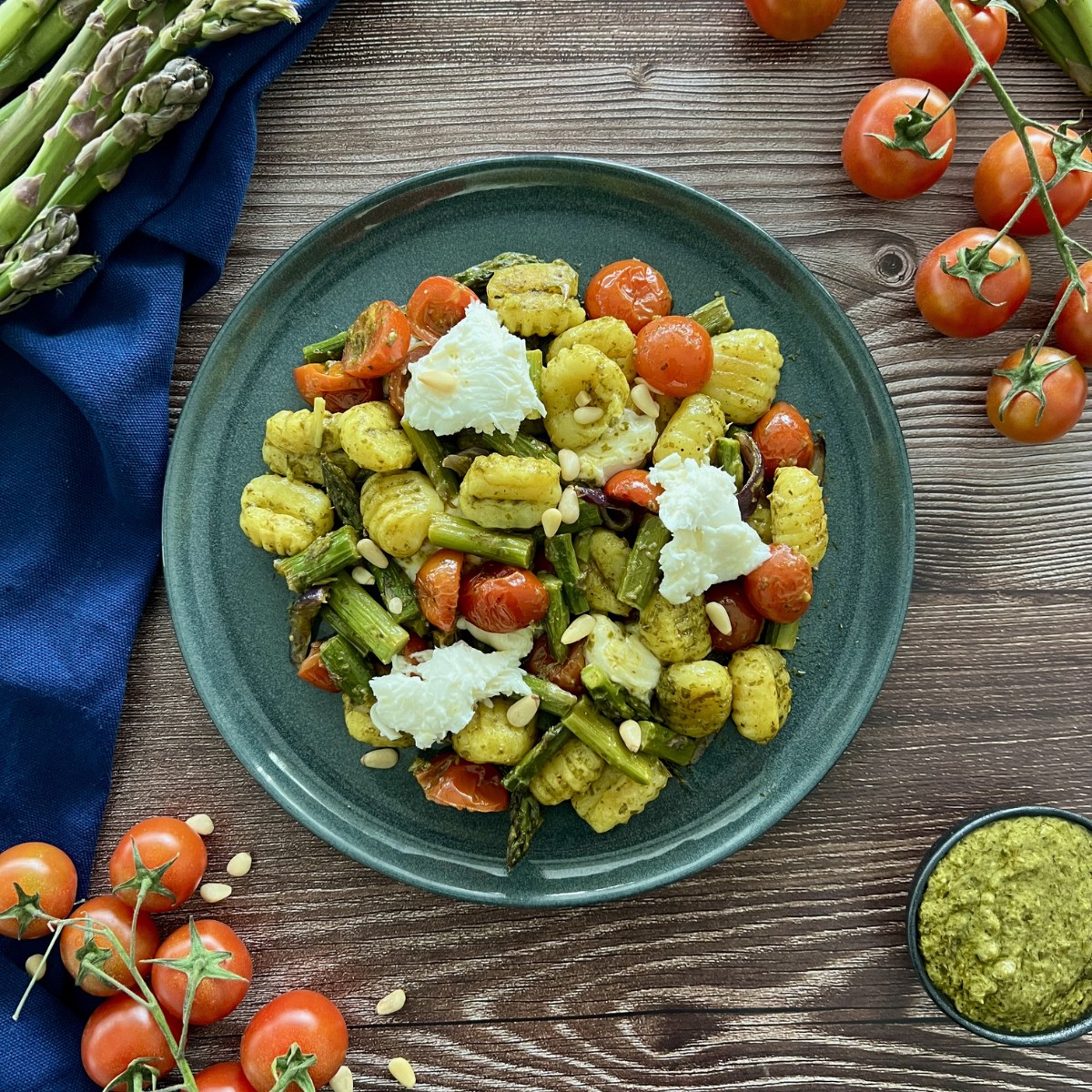 Pesto Gnocchi mit Spagel und Mozzarella auf einem flachen Teller vermischt.