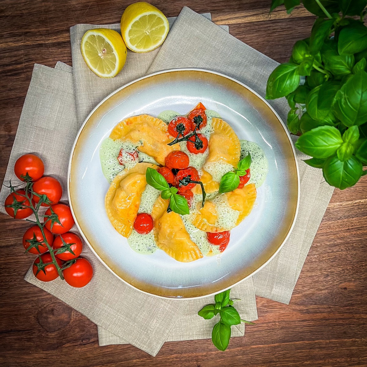 5 Maultaschen auf einem Teller verziert mit Tomaten, KRäutern und Zitrone