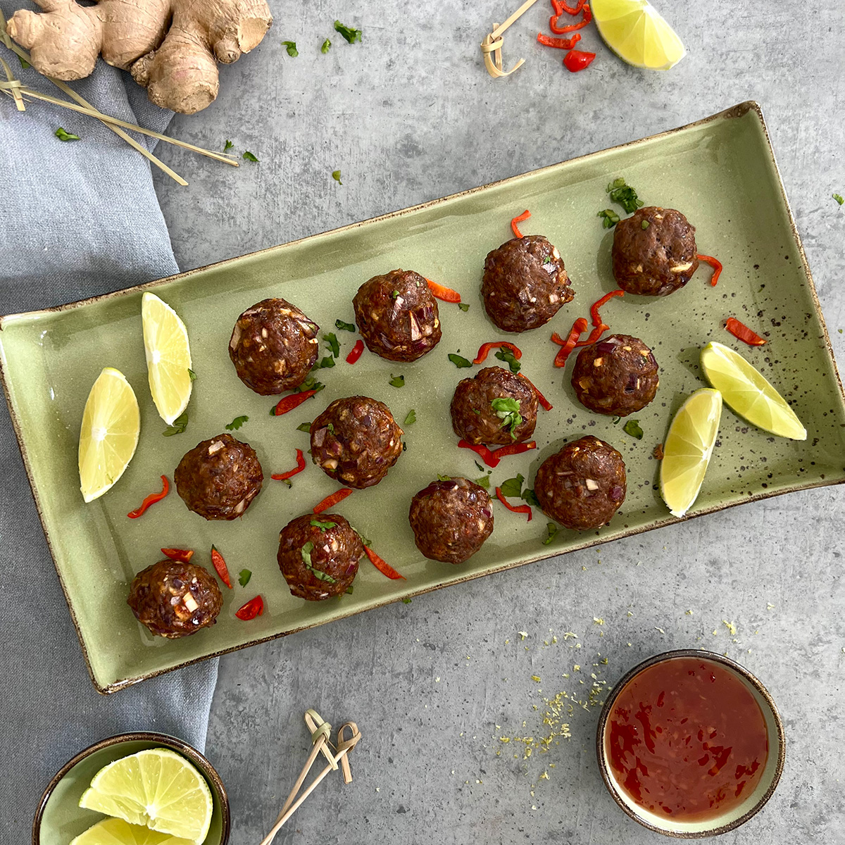 12 Hackbaellchen auf einem grünen Teller verziehrt mit Zitronen