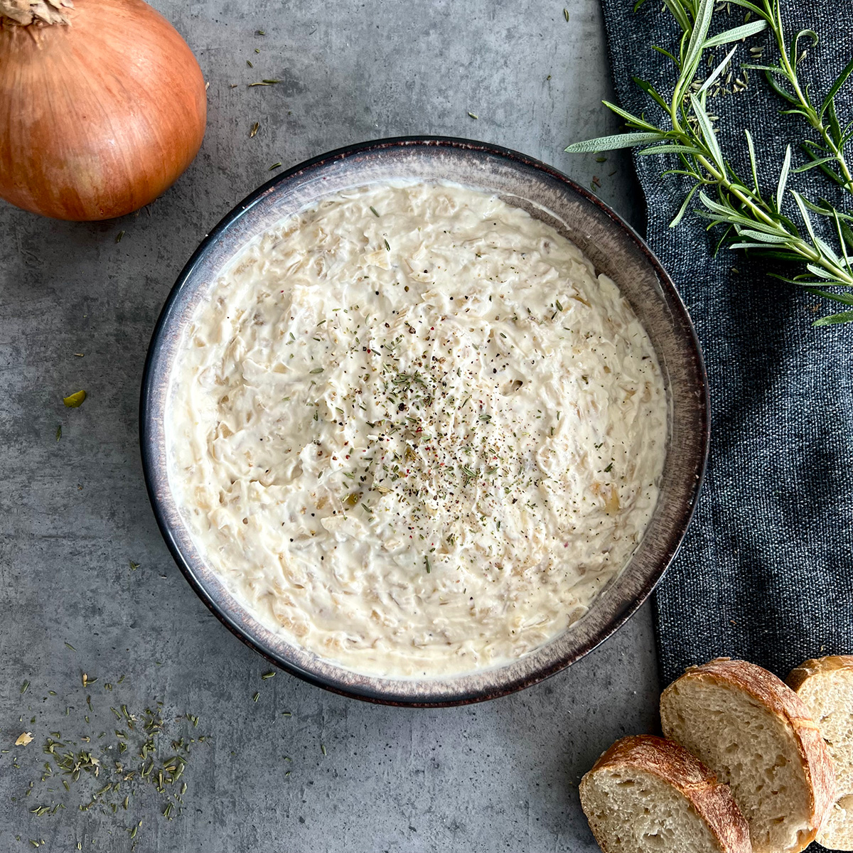 Eine schuessel mit Dip, außen Brot und Zwiebel
