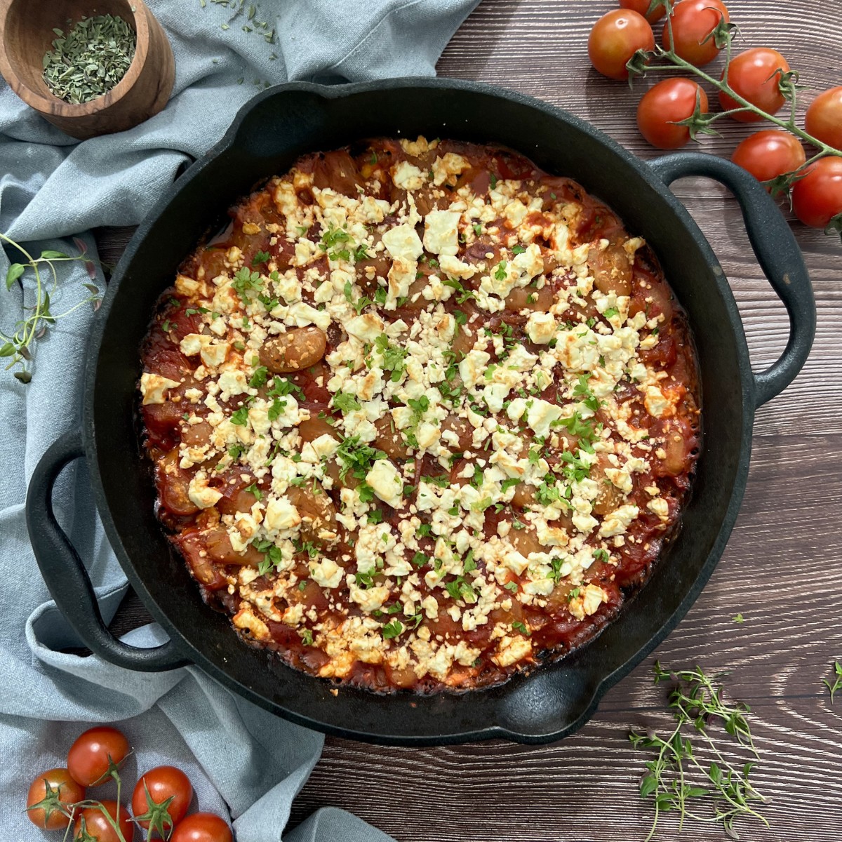 In einer Auflaufform sind Bohnen in einer Tomatensauce mit Kräutern und Feta verfeinert
