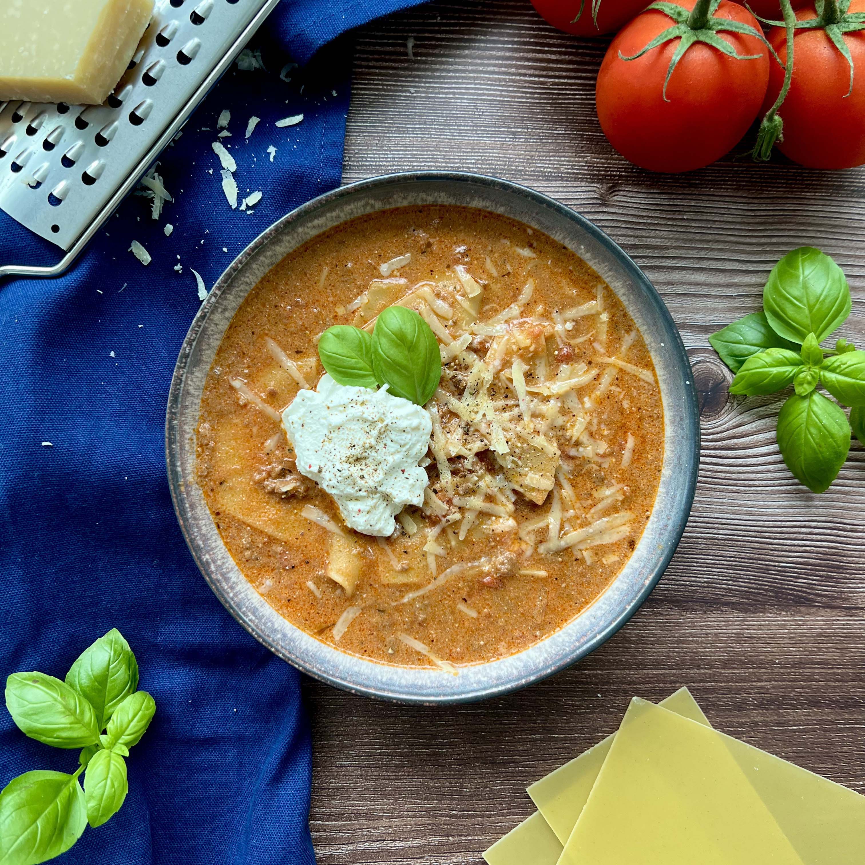 Eine Schüssel gefüllt mit einer Orange BRaunen Lasagne suppe getoppt mit Käse 
