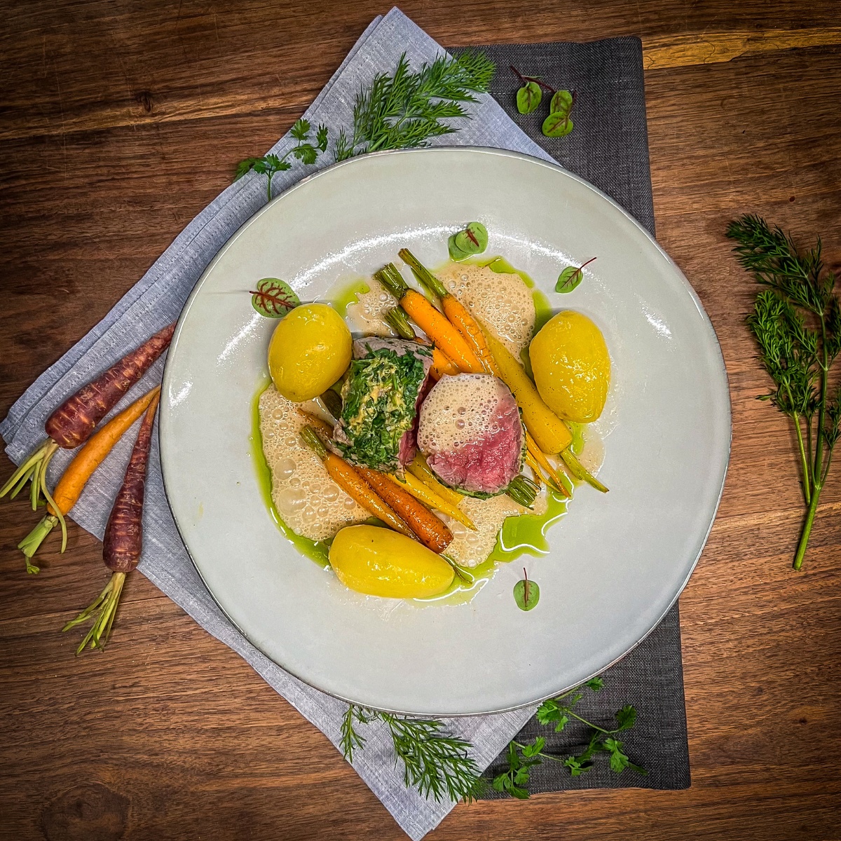 kalbsfiletimkraeutermantellafer auf einem teller verziehrt mit Kräutern