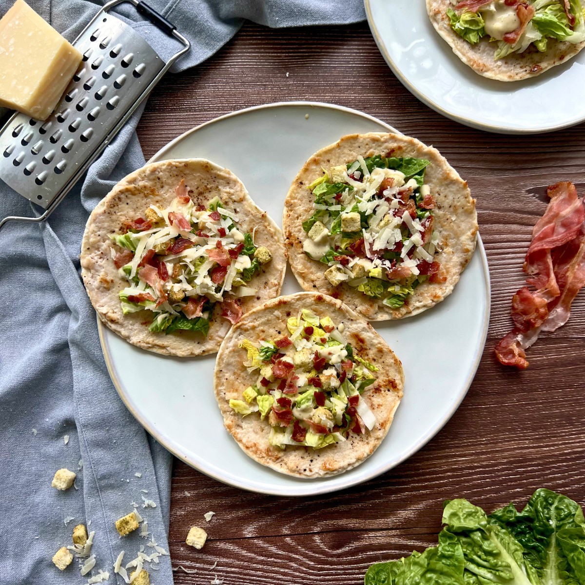 3 Tacos auf einem Teller, daneben Zutaten