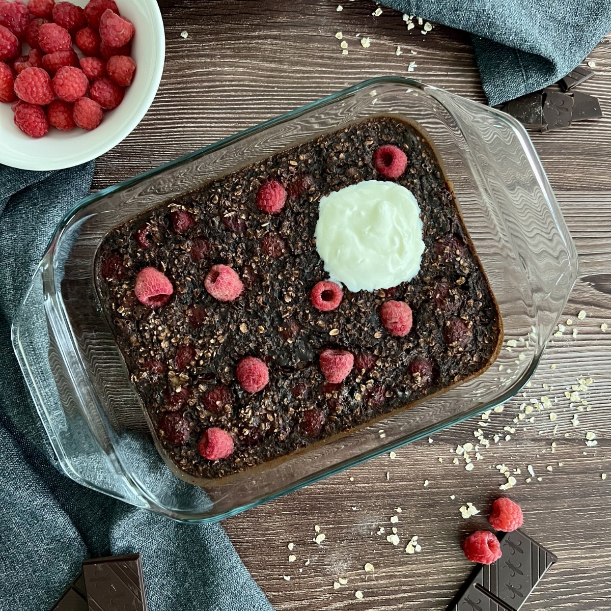 Das Bild zeigt eine Auflaufform mit Brownie darauf sind Himbeeren und Sahne zu sehen.